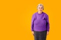 Cheerful octogenarian woman on yellow background with copy space