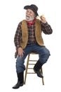 Cheerful old cowboy sits with corn cob pipe Royalty Free Stock Photo