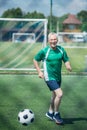 cheerful old man playing football on field Royalty Free Stock Photo