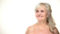 Cheerful old woman with bare shoulders posing on camera, bodycare concept