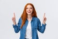 Cheerful outgoing alluring redhead woman, long red hairstyle, showing top promo, pointing fingers up and laughing