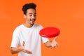 Cheerful outgoing handsome african-american young man with afro haircut, moustache, smiling amused catching red frisbee