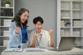 A cheerful Asian senior businesswoman celebrates a project success with a young colleague