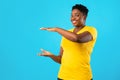 Cheerful Overweight African Woman Holding Invisible Object Over Blue Background Royalty Free Stock Photo