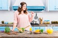 cheerful overweight woman listening music in headphones at table with fresh vegetables in kitchen Royalty Free Stock Photo