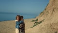 Cheerful pair hugging walking sandy coastline. Happy pair going down to beach.