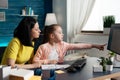 Cheerful parent sitting beside daughter doing school homework together