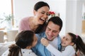 Cheerful parents with small daughters indoors at home, having fun.