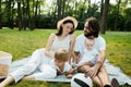 Cheerful parents with two kids dressed in white clothes is sitting on a striped blanket on the lawn on a warm sunny day Royalty Free Stock Photo