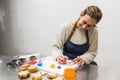 Cheerful pastry chef writing on decorated cookies in pastry shop