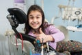 Cheerful patient girl showing thumbs up at dental clinic office. Medicine, stomatology and health care concept