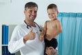 Cheerful pediatrician holding boy in arms