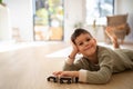 Cheerful pensive small european boy in pajamas lies on floor, plays with cars alone, enjoy rest and spare time Royalty Free Stock Photo