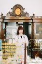 Cheerful pharmacist chemist woman standing in trading hall in vintage pharmacy drugstore Royalty Free Stock Photo