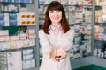 Cheerful pharmacist chemist woman in white coat standing in pharmacy drugstore and holding in her hands many colorful Royalty Free Stock Photo