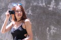 Cheerful photographer woman with sunglasses holding camera taking photo in city. Traveler young girl use digital camera take Royalty Free Stock Photo