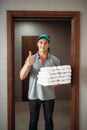 Cheerful pizza delivery boy shows Ok symbol Royalty Free Stock Photo