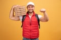 Cheerful pizza delivery man stands with carton boxes, waits for client, wears white cap and white tshirt with red waistcoat, poses Royalty Free Stock Photo