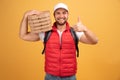 Cheerful pizza delivery man stands with carton boxes, waits for client, wears white cap and white tshirt with red waistcoat, poses Royalty Free Stock Photo