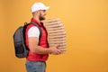 Cheerful pizza delivery man stands in profile with carton boxes, waits for client, wears white cap and white tshirt with red Royalty Free Stock Photo