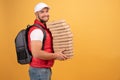 Cheerful pizza delivery man stands in profile with carton boxes, waits for client, wears white cap and white tshirt with red Royalty Free Stock Photo