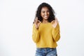 Cheerful pleased dark-skinned girl student in yellow sweater smiling with approval and delight, show okay good gesture