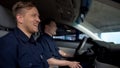 Cheerful police mates laughing in patrol car during daily duty, friendship Royalty Free Stock Photo