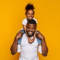 Cheerful portrait of black dad and daughter over yellow background