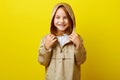 Cheerful portrait of happy little girl in demi-season beige jacket with hood from rain, studio shot on colored