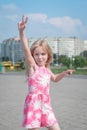 Cheerful portrait of a little five year old girl in a pink summer dress on the streets of her city Royalty Free Stock Photo