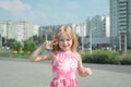 Cheerful portrait of a little five year old girl in a pink summer dress on the streets of her city Royalty Free Stock Photo