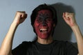 Cheerful portrait of a man with the flag of the Albania painted on his face on grey background. Royalty Free Stock Photo