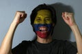 Cheerful portrait of a man with the flag of the Colombia painted on his face on grey background. Royalty Free Stock Photo