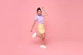 Cheerful positive Asian girl jumping in the air with raised fists looking at camera isolated on pink background Royalty Free Stock Photo