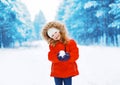 Cheerful positive child with snowball having fun outdoors