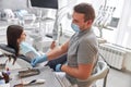Cheerful positive dentist and client in dentistry. Female client sit in chair