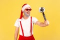 Cheerful positive man in stylish sunglasses and santa claus hat holding smartphone on selfie stick, recording video or making Royalty Free Stock Photo