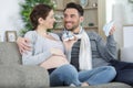 cheerful pregnant couple playing together with baby shoes at home Royalty Free Stock Photo