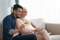 Cheerful pregnant muslim couple shopping online, using credit card and digital tablet Royalty Free Stock Photo