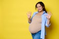 Cheerful pregnant woman expecting a baby, showing number nine with her fingers, 9 month of happy carefree pregnancy