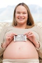 Cheerful pregnant woman holding an echography