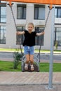 A cheerful preschool girl swings on a swing in the playground