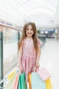 Cheerful preschool girl walking with shopping bags. Pretty smiling little girl with shopping bags posing in the shop. The concept