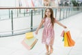 Cheerful preschool girl walking with shopping bags. Pretty smiling little girl with shopping bags posing in the shop. The concept