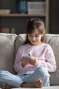 Cheerful preschool sweet kid girl using smartphone home alone
