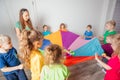 Teacher and kindergarten kids playing with colorful parachute Royalty Free Stock Photo