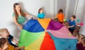 Teacher and kindergarten kids playing with colorful parachute Royalty Free Stock Photo