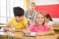 Inquisitive preteen boy peeking at workbook of cute smiling girl in class Royalty Free Stock Photo