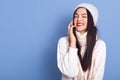 Cheerful pretty brunette girl talking on phone and laughing carefree, holding smartphone near ear, standing isolated over blue
