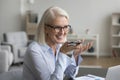 Smiling mature businesswoman speak on speakerphone using mobile phone Royalty Free Stock Photo